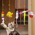 Five Mewnook door bouncer cat toys hanging on elastic cords while a cat bats at one